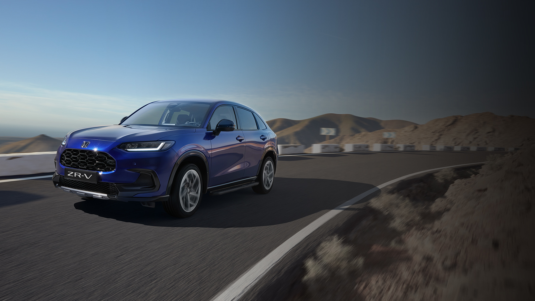 Elölről készült, háromnegyed felvétel a Honda ZR-V-ről a Robust csomaggal hegyvidéki környezetben.